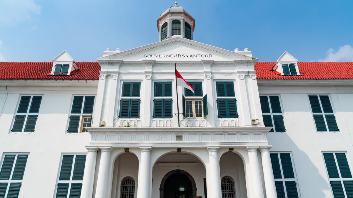 Front view of the Jakarta History Museum with clear skies and Indonesian flag.